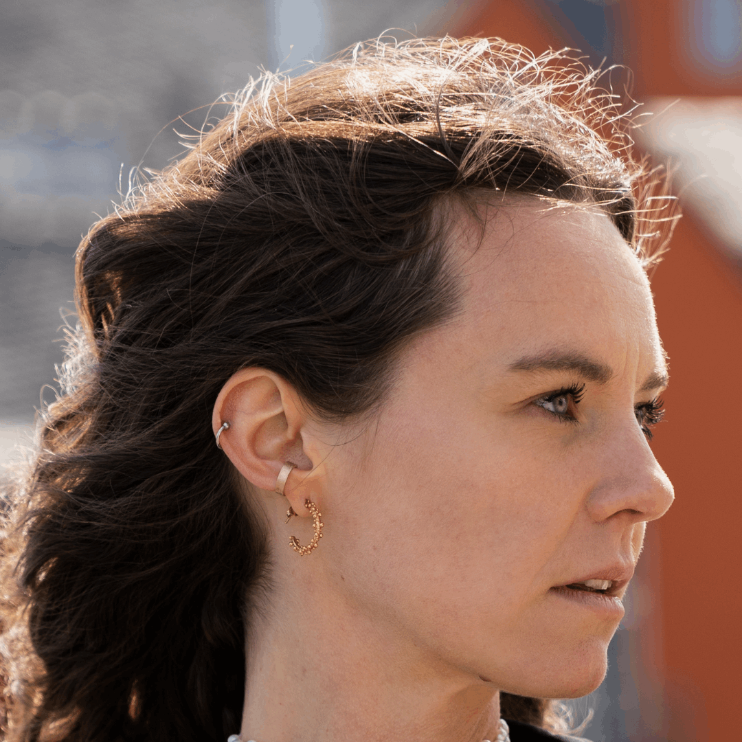 Moderner Earcuff 'Anicca klein' aus recyceltem 925er Sterling Silber oder 14k Echtgold, getragen am Modell im Seitenprofil mit anderem Schmuck; handgefertigter Schmuck aus nachhaltigen Materialien in Deutschland.